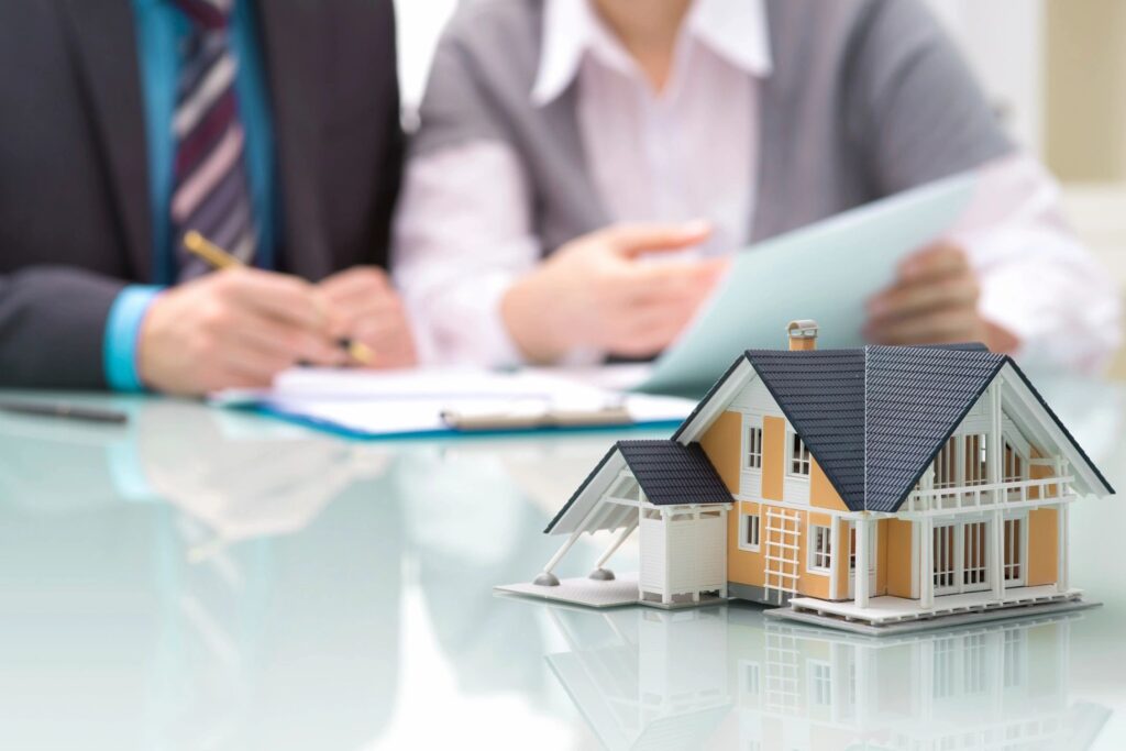small house replica on a table with people behind looking at paper